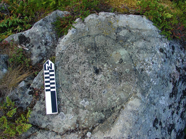 Rock inscription of a simple compass rose, with a line and the letter 'N', perfectly aligned with true north. A hole at the centre of the circle would have been used with a straight stick to cast a shadow at noon, to find true north.